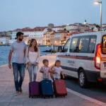 De l’aéroport de Dubrovnik au centre-ville avec enfants : rentrer sereinement après une arrivée tardive Une famille avec deux enfants avance avec ses bagages vers une navette éclairée à l’aéroport de Dubrovnik au crépuscule.